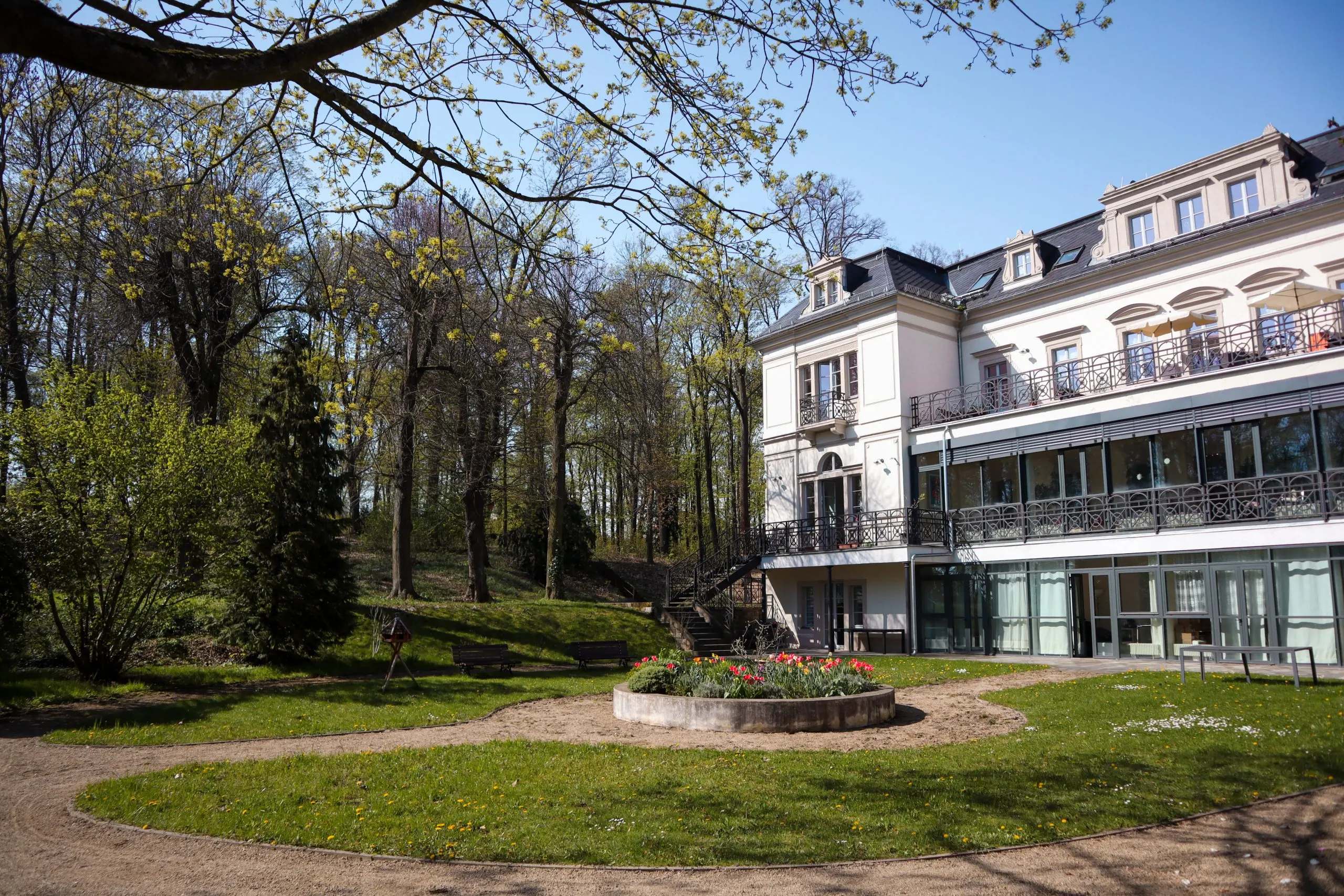 Standort Katharinenhof Meißen-Plossen: Hauptgebäude vom Garten aus mit blühender Bepflanzung im Frühling