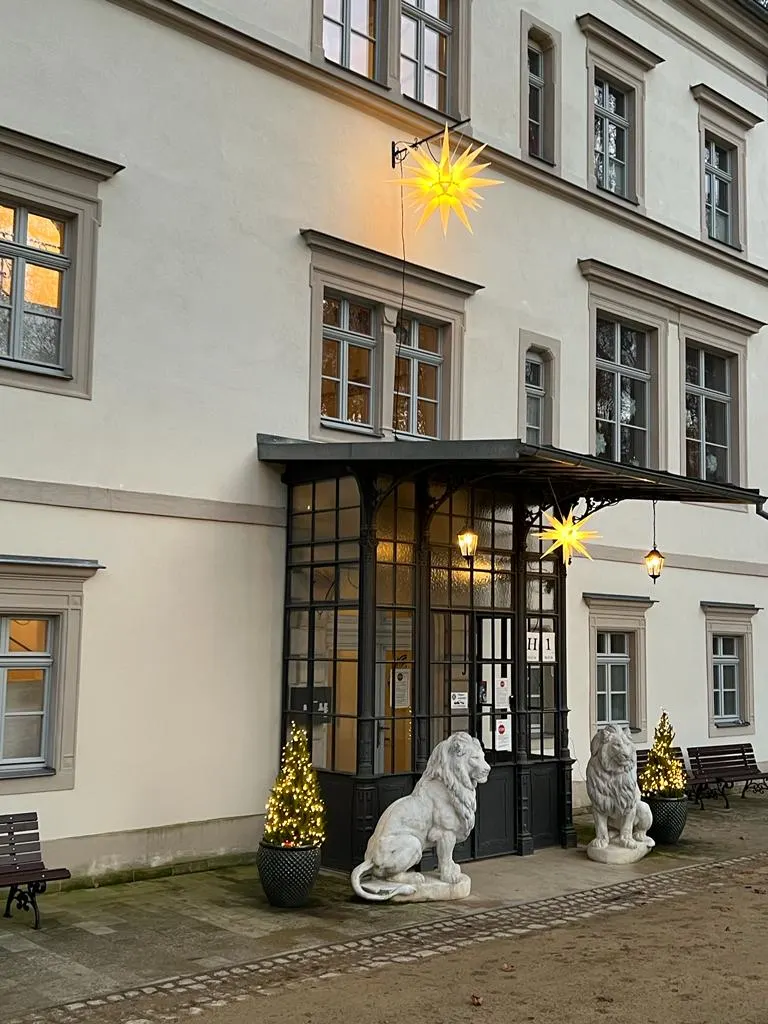 Eingang Haus 1 des Katharinenhofs Meißen mit beleuchtetem Herrnhuter Weihnachtsstern, Löwenfiguren und kleinen Tannenbäumen